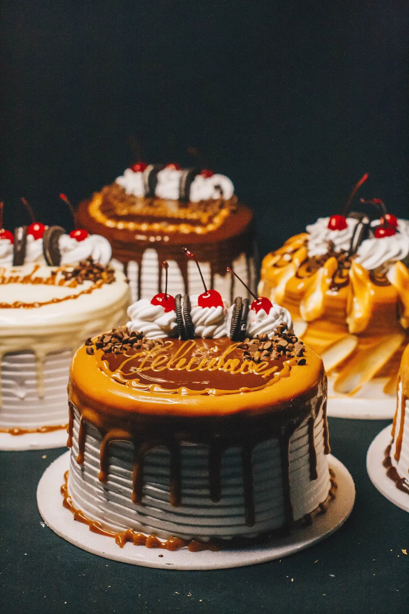 Whole celebration cakes finished with caramel drip, cream and cherries